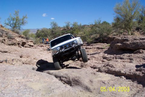 1993 Ford Bronco - White Ford Bronco tackles a challenging off-road course with steep inclines and rocky obstacles.