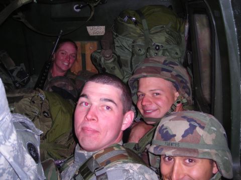 2003 Jeep TJ - Four soldiers are packed inside a military vehicle, with gear piled around them. One soldier's helmet has the name "FUENTES" visible.