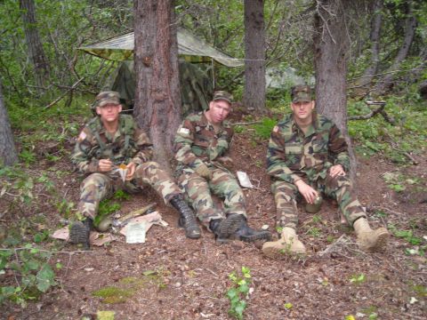 2003 Jeep TJ - Three soldiers take a break in a wooded area, with a tent set up behind them.