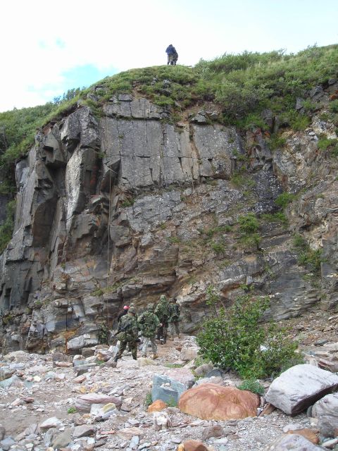 2003 Jeep TJ - Military personnel descend a cliff face using ropes, with a rocky, debris-strewn area at the base.