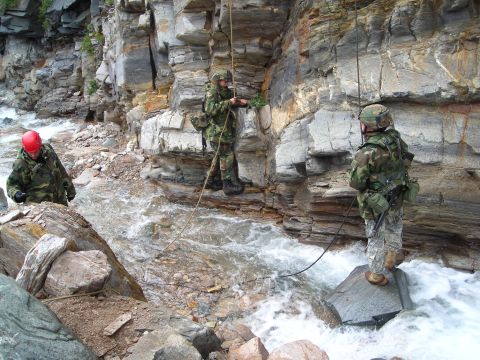 2003 Jeep TJ - Soldiers navigate a challenging terrain, rappelling down a rocky gorge beside a rushing river.