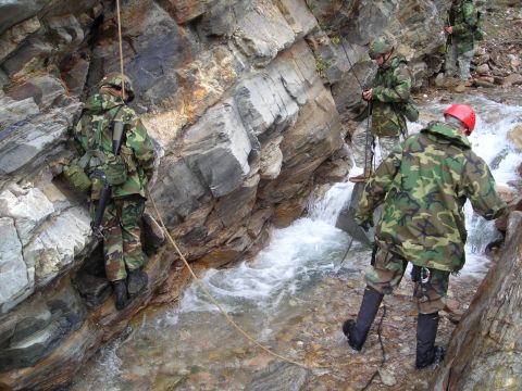 2003 Jeep TJ - Soldiers navigate a rocky terrain with a flowing stream, using ropes for descent.