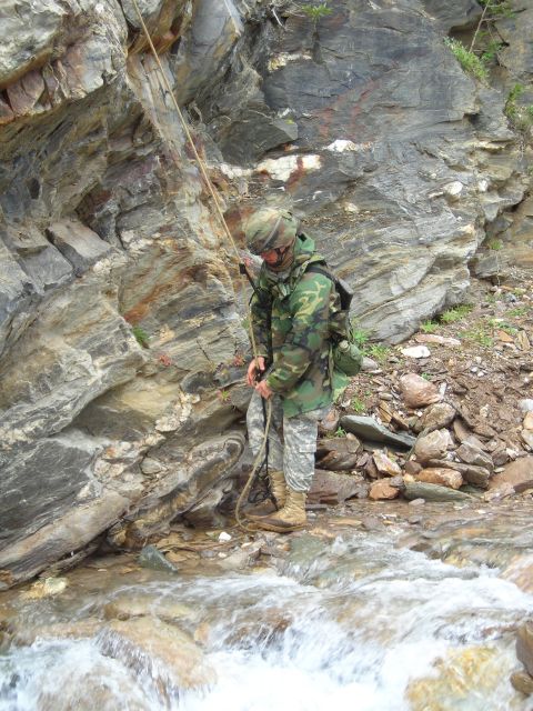2003 Jeep TJ - A soldier uses a rope to descend a rocky slope beside a flowing stream.