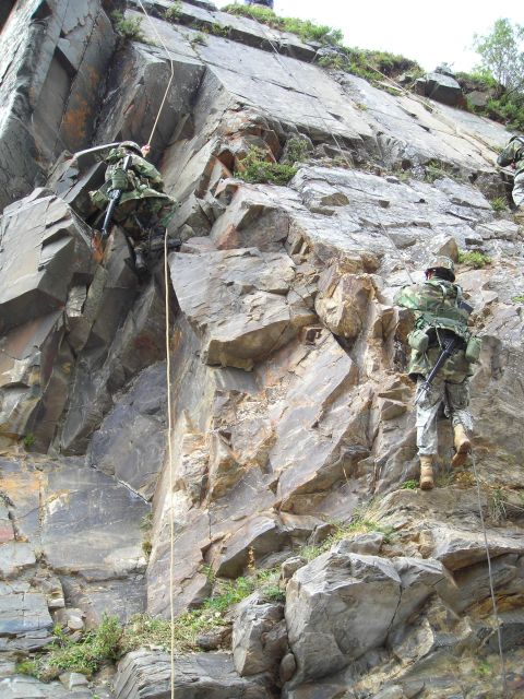 2003 Jeep TJ - Military personnel practice rappelling techniques on a rock formation.
