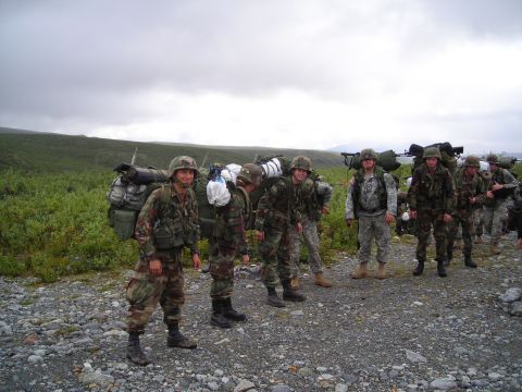 2003 Jeep TJ - A group of soldiers carrying heavy packs stand ready for a mission in a barren landscape.
