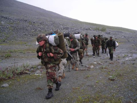 2003 Jeep TJ - A column of soldiers traverses a desolate, mountainous terrain, each burdened with substantial camping equipment.
