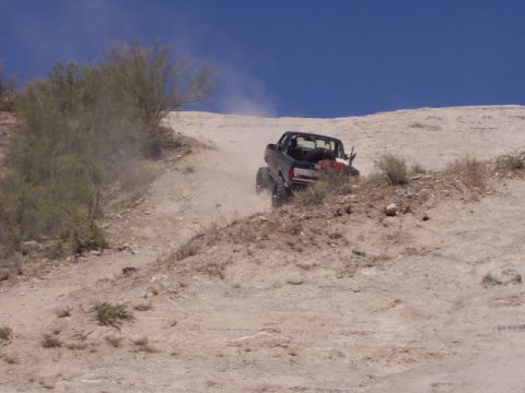 1993 Ford Bronco - A black Ford Bronco navigates a steep, dusty incline under a clear blue sky.