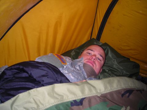 2003 Jeep TJ - A soldier rests inside a tent, surrounded by sleeping gear and the tent's yellow fabric.