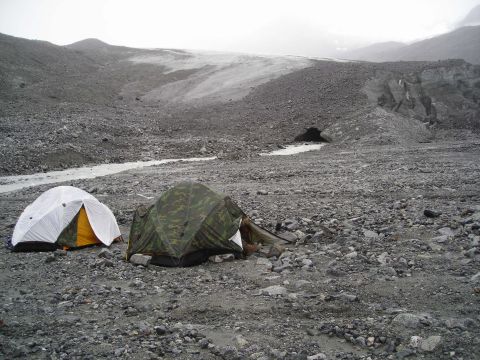 2003 Jeep TJ - A campsite with two tents is established on a rocky, desolate landscape, with a glacier visible in the background.
