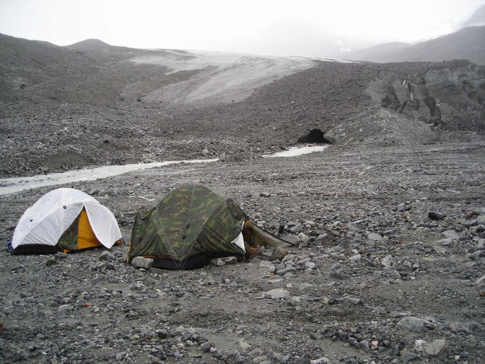 Two tents on rocky terrain with a glacier in the distance