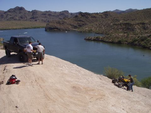 1993 Ford Bronco - Two vehicles, a pickup truck and an ATV, are parked near a body of water with mountainous terrain in the background.
