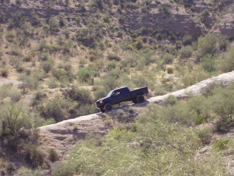 1993 Ford Bronco - A 1993 Ford Bronco navigates a dusty trail on a dry, scrub-covered hillside.