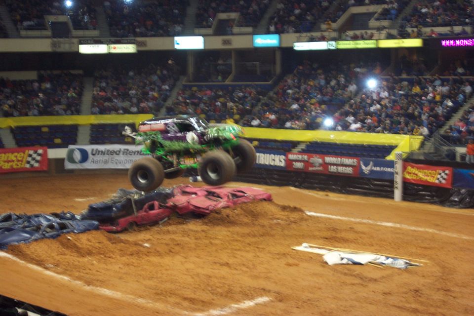 Monster truck airborne over crushed cars in an arena