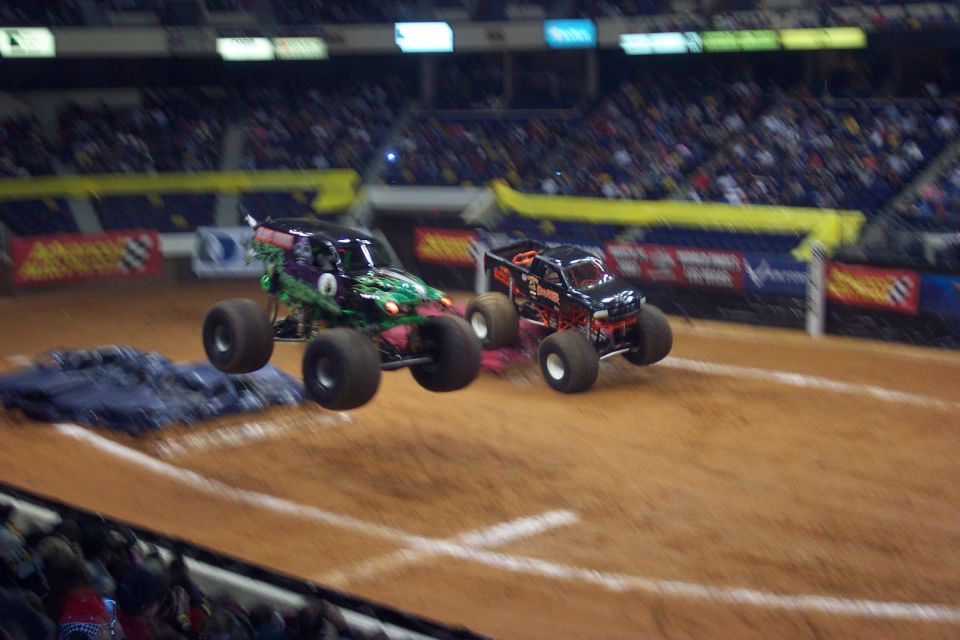 Two monster trucks airborne over a dirt track during a competition