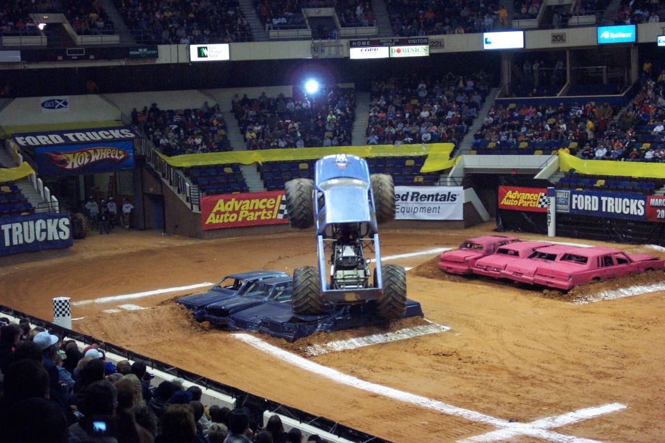 Monster truck airborne over crushed cars in an arena