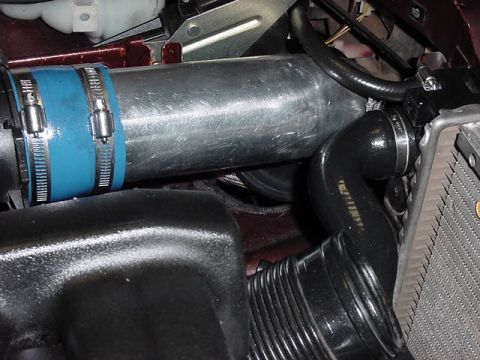 1984 BMW 3 Series - Close-up of engine intake piping with a blue coupler and metal clamps, next to a radiator.