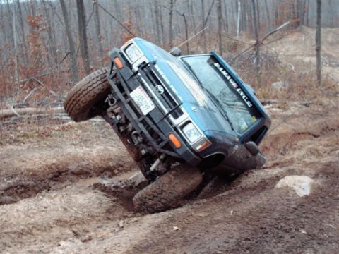 1977 Ford F-150 - Off-road SUV stuck in a muddy ditch, showing 'DAMAGE INC.S' on the windshield.