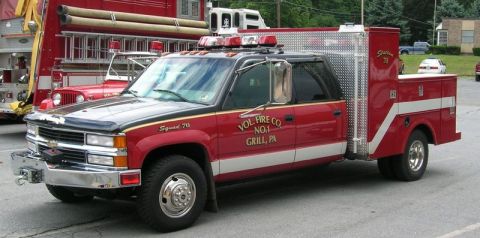 1989 Ford Bronco - A red and black crew cab truck with a service body, marked "Squad 70" and "VOL. FIRE CO. NO. 1 GRILL, PA", is parked near other fire vehicl…