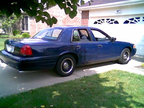 2001 Ford Crown Victoria - A blue 2001 Ford Crown Victoria is parked in front of a garage.