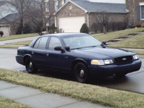 2001 Ford Crown Victoria - A dark blue 2001 Ford Crown Victoria police car is parked on the side of a residential street.