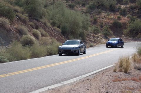 2006 Mazda RX-8 - Two cars travel along a desert highway, with a Mazda RX-8 in the foreground.