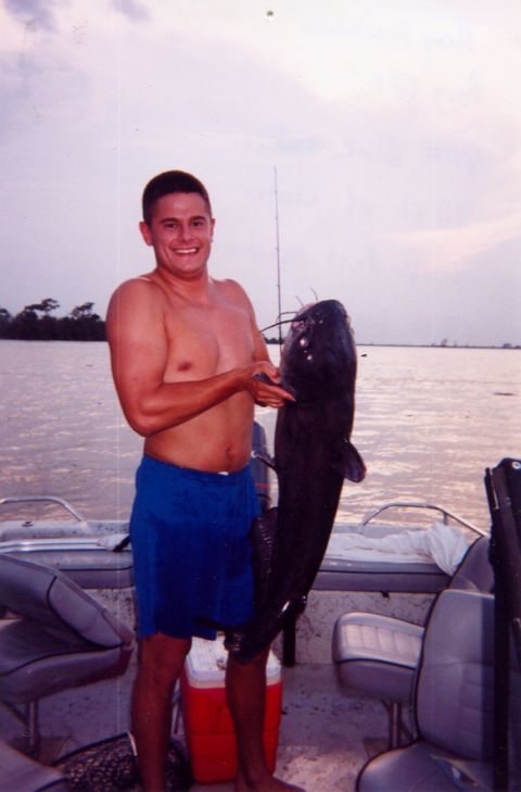 1992 Ford Bronco - A man proudly displays a large catfish he caught while on a boat, with another boat in the background.