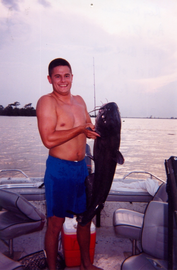 Man on a boat holding a large catfish