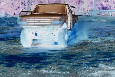 1995 Ford Bronco - Ford Bronco kicks up water while driving off-road.