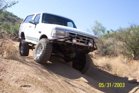 1993 Ford Bronco - This 1993 Ford Bronco is captured mid-climb on a sandy, off-road trail, its lifted suspension and aggressive tires.