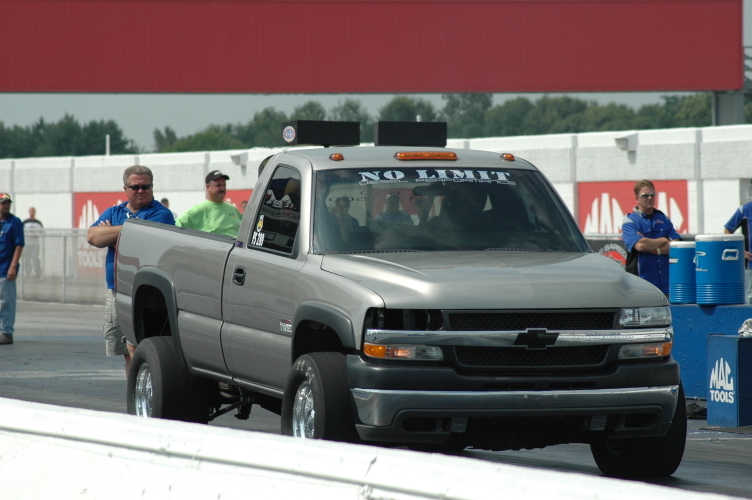 Gray Chevrolet pickup with NO LIMIT windshield banner launching at a drag strip