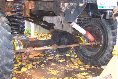 1978 Ford Bronco - This photo shows the rusty undercarriage of a vehicle, focusing on the front axle and suspension components.