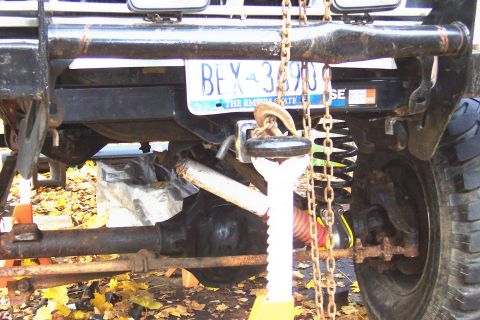 1978 Ford Bronco - The rear suspension and axle of a vehicle are visible, supported by jack stands and chains.