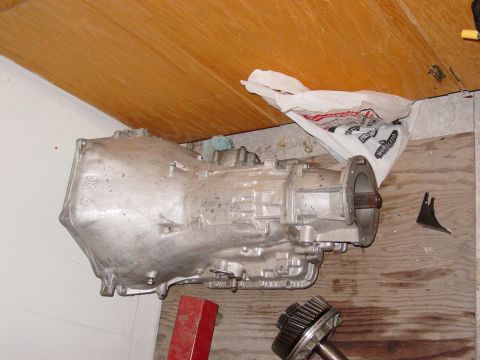 1979 Ford Bronco - A transmission part is shown on a wooden surface, with a white plastic bag in the background.