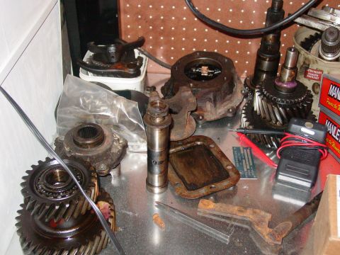 1979 Ford Bronco - A collection of used transmission parts, including gears and housings, are spread across a workbench.