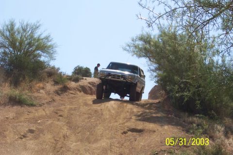 1993 Ford Bronco - A silver 1993 Ford Bronco navigates an off-road trail on a sunny day.