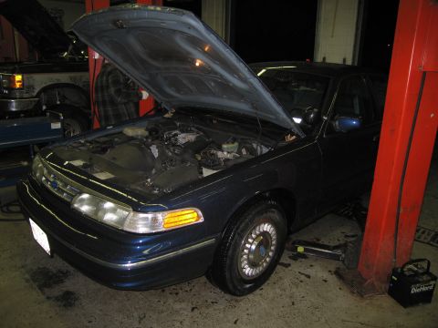 1991 Ford LTD Crown Victoria - A dark blue sedan is parked in a garage with its hood open, showing the engine compartment.