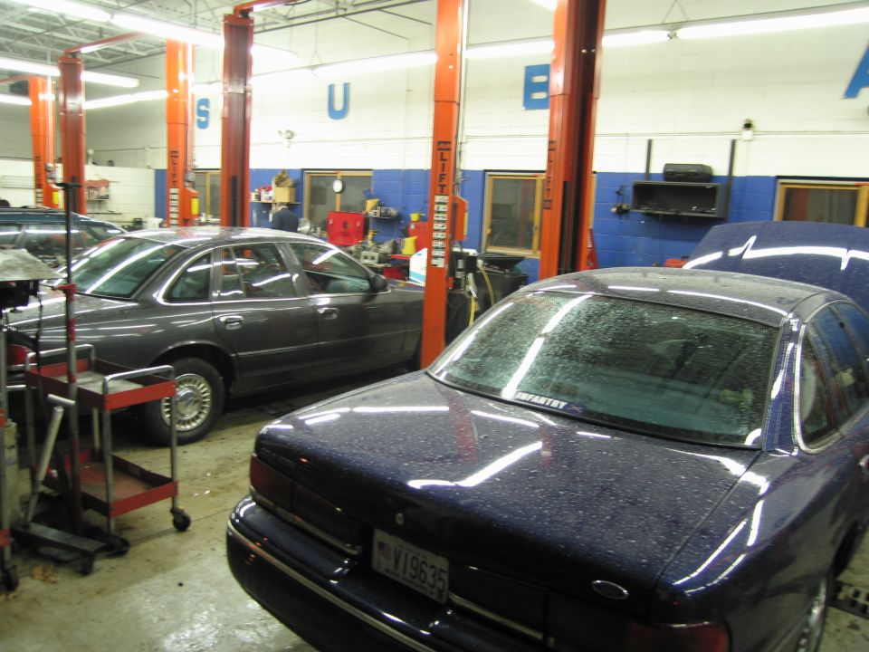 Rear view of a dark blue sedan with a license plate V19635, parked in a garage