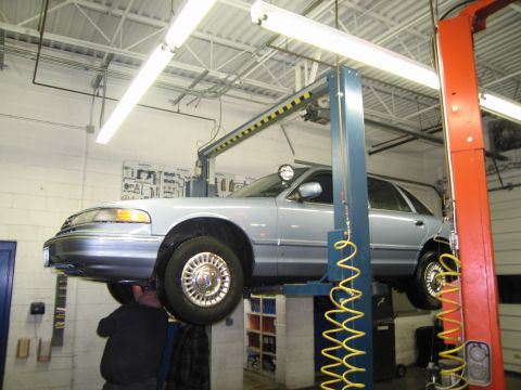 1991 Ford LTD Crown Victoria - A mechanic works on a 1991 Ford Crown Victoria LTD being serviced on a car lift.