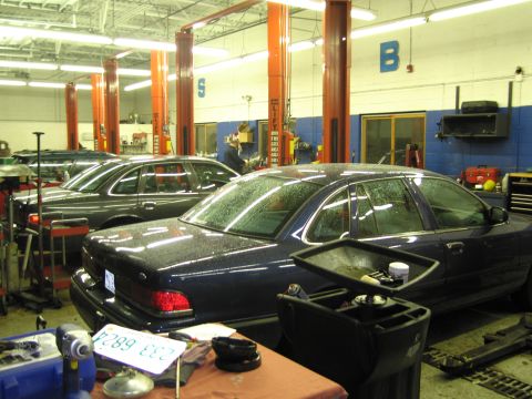 1991 Ford LTD Crown Victoria - A 1991 Ford Crown Victoria LTD is parked in a dealership service bay alongside other vehicles.