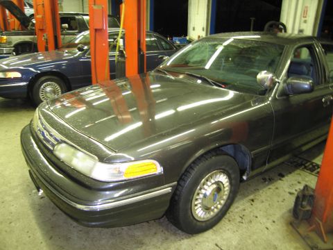 1991 Ford LTD Crown Victoria - A dark gray Ford Crown Victoria is parked in a garage, with another blue Crown Victoria behind it.