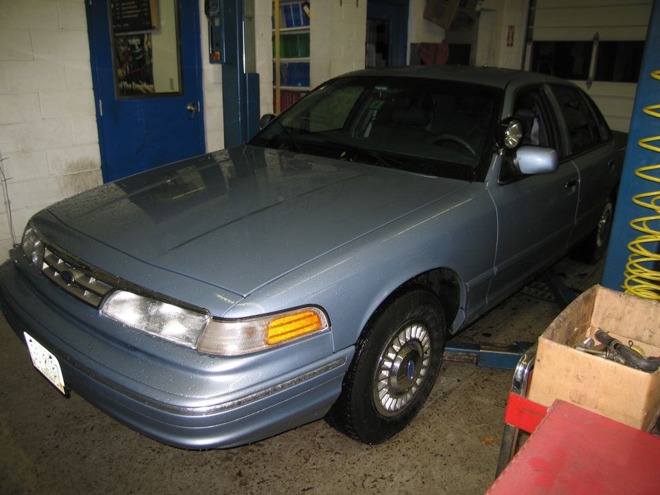 Light blue 1991 Ford Crown Victoria parked in a garage, on a lift
