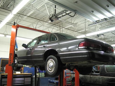 1991 Ford LTD Crown Victoria - Dark gray 1991 Ford Crown Victoria LTD is raised on a service lift inside a garage.