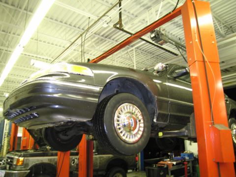 1991 Ford LTD Crown Victoria - A 1991 Ford Crown Victoria LTD is shown on a car lift in a service bay, with another vehicle visible in the background.