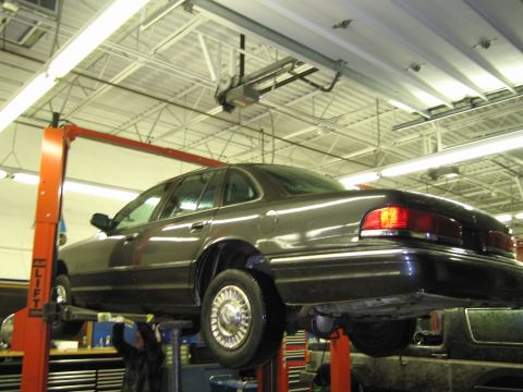 1991 Ford LTD Crown Victoria - Dark 1991 Ford Crown Victoria LTD is raised on a service lift in a garage.