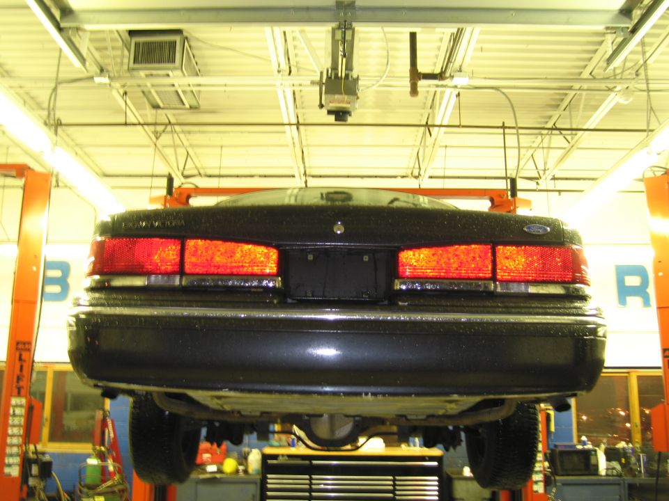 Rear view of a black 1991 Ford Crown Victoria on a lift in a garage