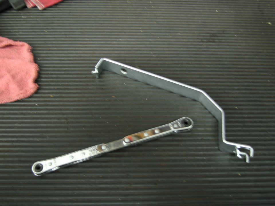 Two metal automotive tools on a ribbed black surface with a pink cloth