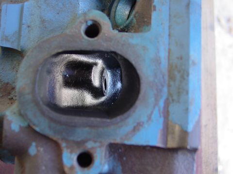1979 Ford Bronco - A close-up view of an engine cylinder head, showing a dark, reflective intake port and signs of rust.