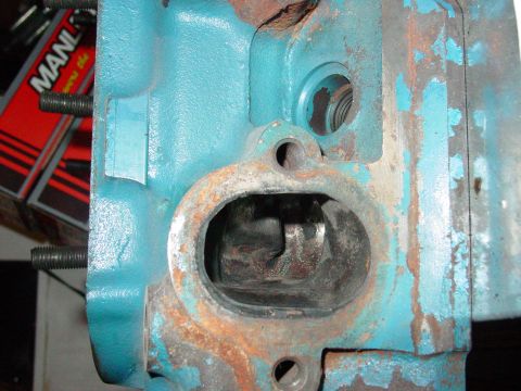 1979 Ford Bronco - This is a close-up view of an engine cylinder head part, showing rust and teal paint.