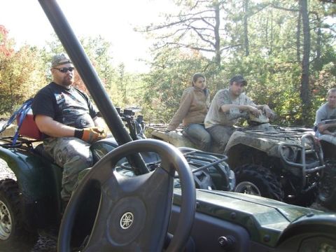 1987 Suzuki Samurai - A group of people are riding ATVs through a wooded area on a sunny day.