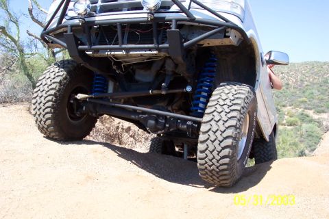 1993 Ford Bronco - Close-up view of the front wheel and suspension system of an off-road vehicle, modified for terrain.